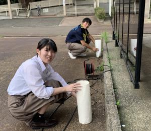 高校生が外で行灯を設置している様子(写真)