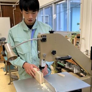 電動ノコギリで木材を加工している様子(写真)