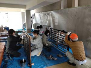 格子の塗装作業の様子 町内会の有志の皆さんと上越総合技術高等学校の生徒さんが協力して作業しています(写真)