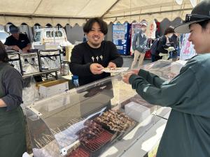 飲食ブースで浜焼きを買う人と店員（写真）