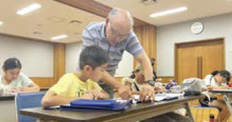 小学生が先生のアドバイスを聞く様子（写真）