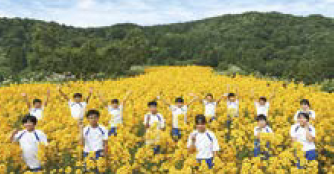 ヤナギバひまわりの花畑と、イベントの運営に参加した安塚小学校の生徒（写真）