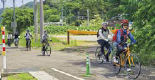 自転車で一列になって走るツアー参加者（写真）